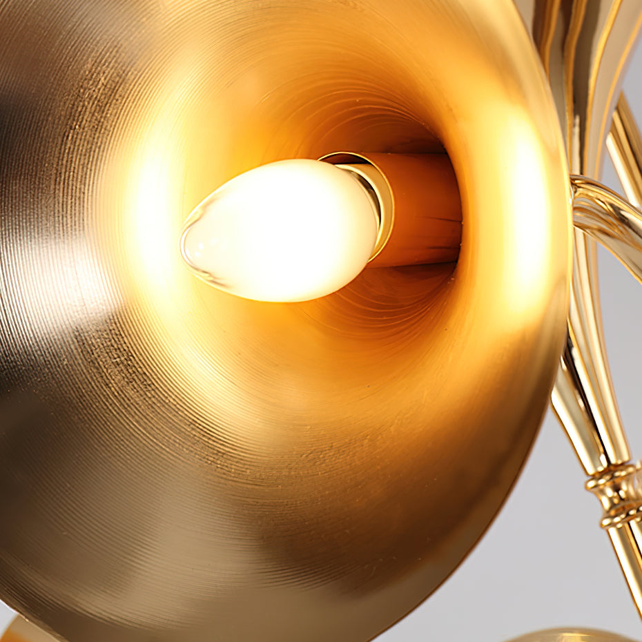 Close view of a gold horn on this Clérachic chandelier, its polished inner surface glowing around a candle-style bulb.
