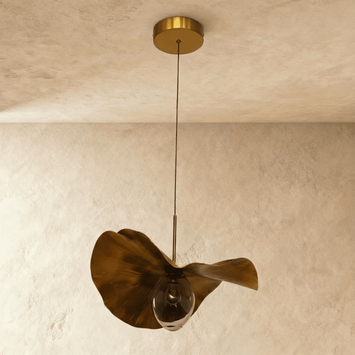 Clérachic pendant with a rippled gold-finish metal shade and a clear glass bulb, switched off, on a thin cord from a brass canopy.