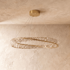 Clérachic gold twisted ring chandelier with rows of clear crystal bars, five suspension cables and a round gold ceiling canopy.