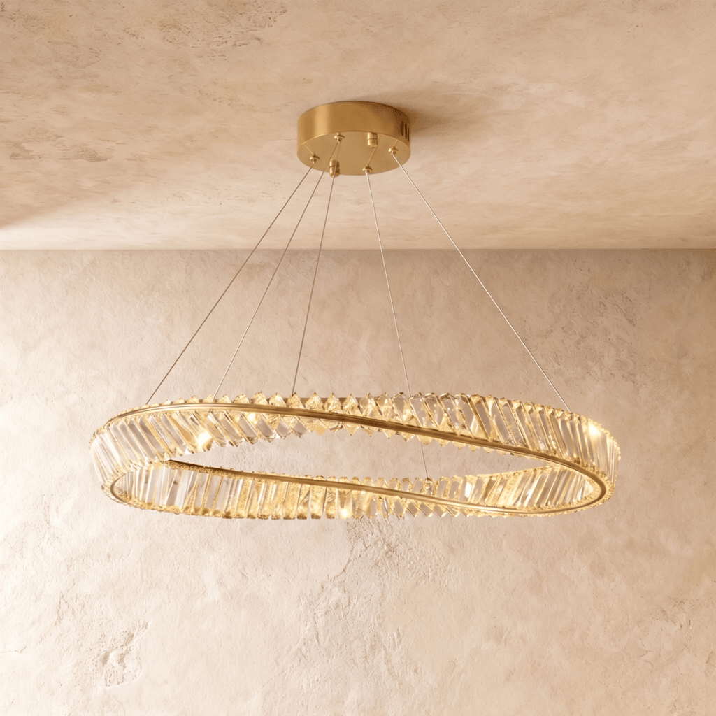 Clérachic mid-size twisted gold ring chandelier of clear crystal bars on slim cables, photographed against textured plaster walls.