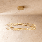 Clérachic mid-size twisted gold ring chandelier of clear crystal bars on slim cables, photographed against textured plaster walls.