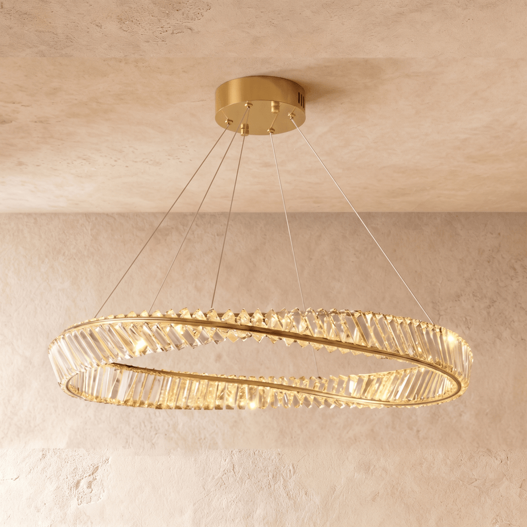 Clérachic wide gold crystal ring chandelier on cables, shown against pale plaster with a gold ceiling canopy and warm light.