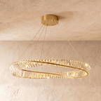Clérachic wide gold crystal ring chandelier on cables, shown against pale plaster with a gold ceiling canopy and warm light.