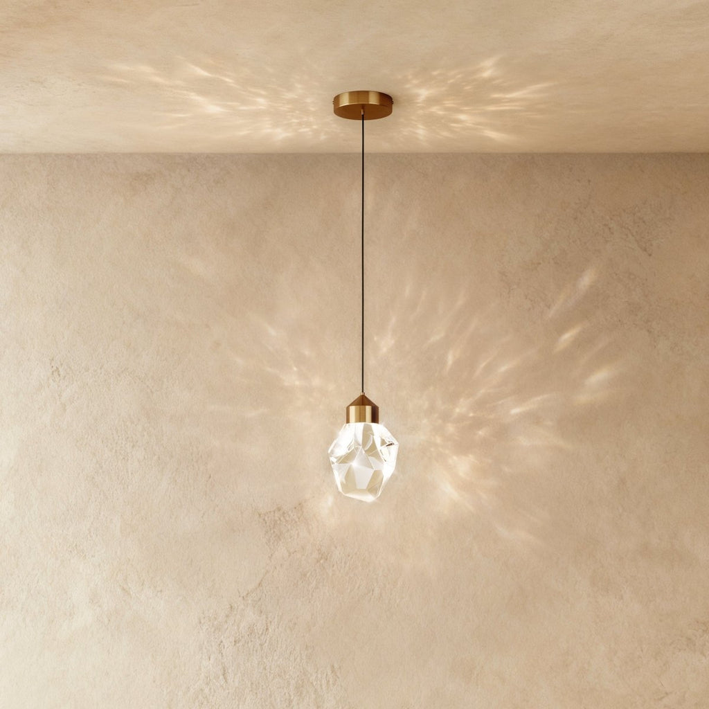 Clérachic crystal drop pendant light with brass mount throws overlapping starburst shadows across a warm plaster wall.