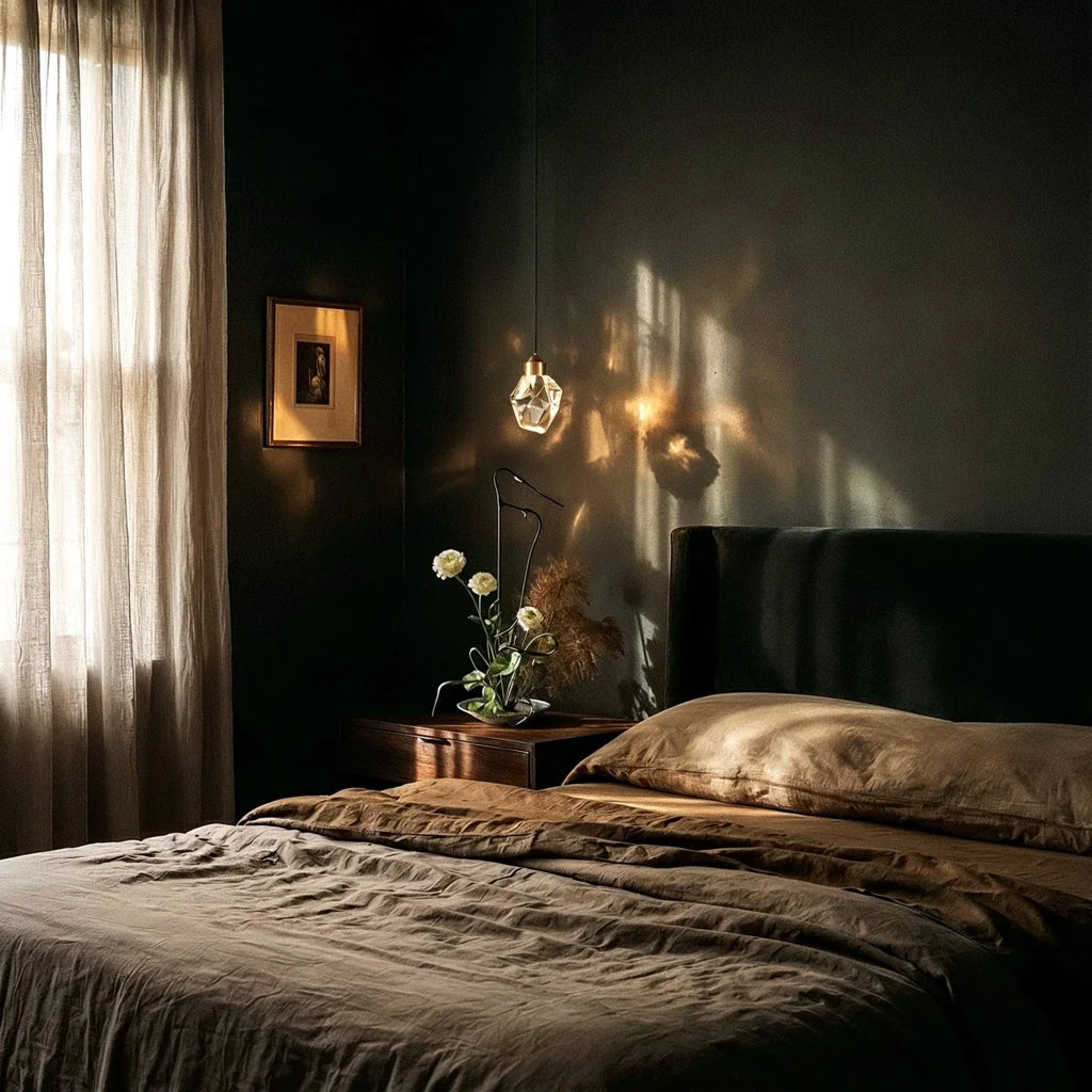 Clérachic crystal drop pendant light glowing above a dark bedroom nightstand, faceted glass catching warm lamplight.