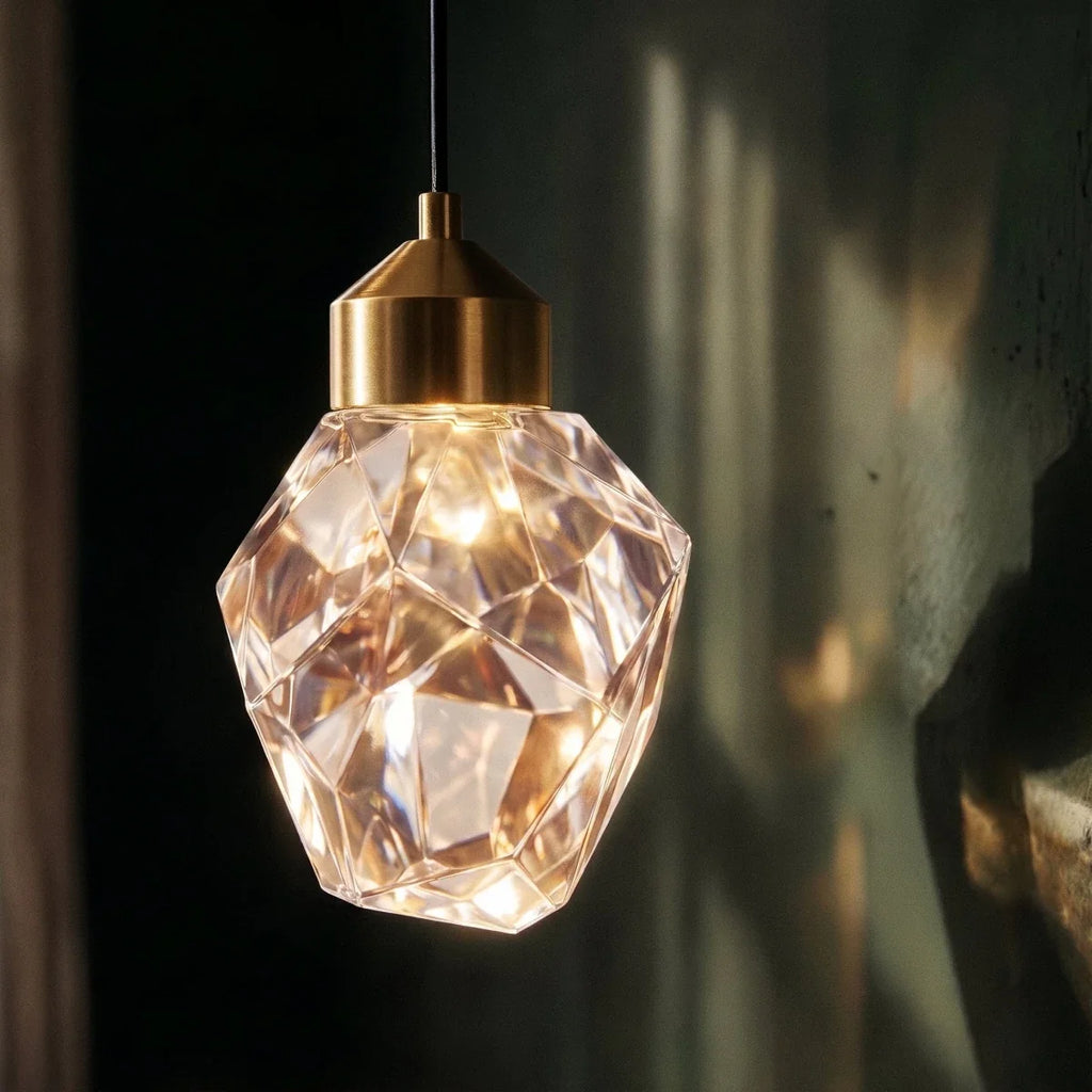 Detail of the Clérachic crystal drop pendant's angular faceted glass shade and brushed brass fitting against a dark backdrop.