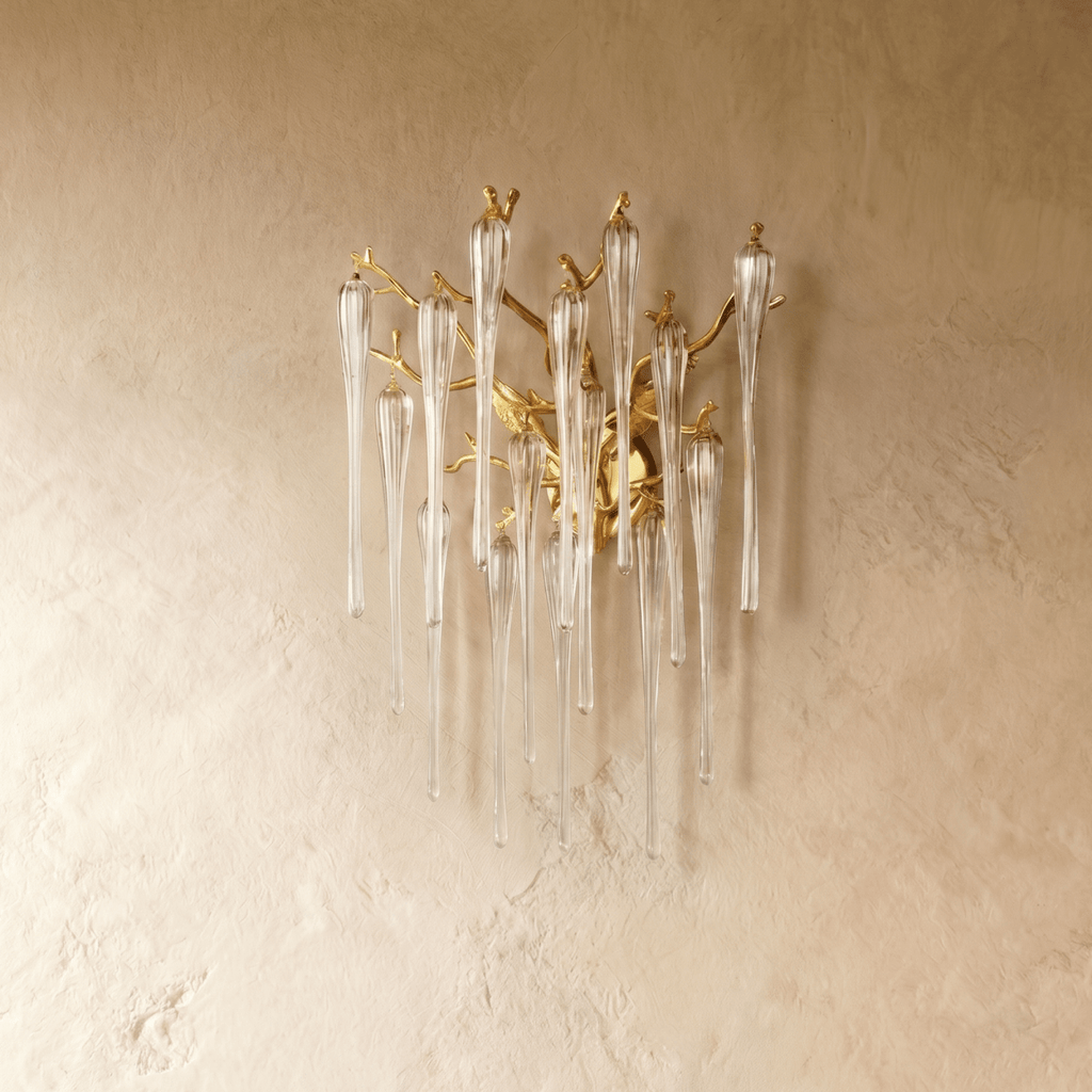 Clérachic gold branch wall lamp with long clear glass icicle drops, switched off against a warm textured plaster wall.