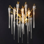 Clérachic gold branch wall lamp with clear glass drops glowing against a dark charcoal studio backdrop.