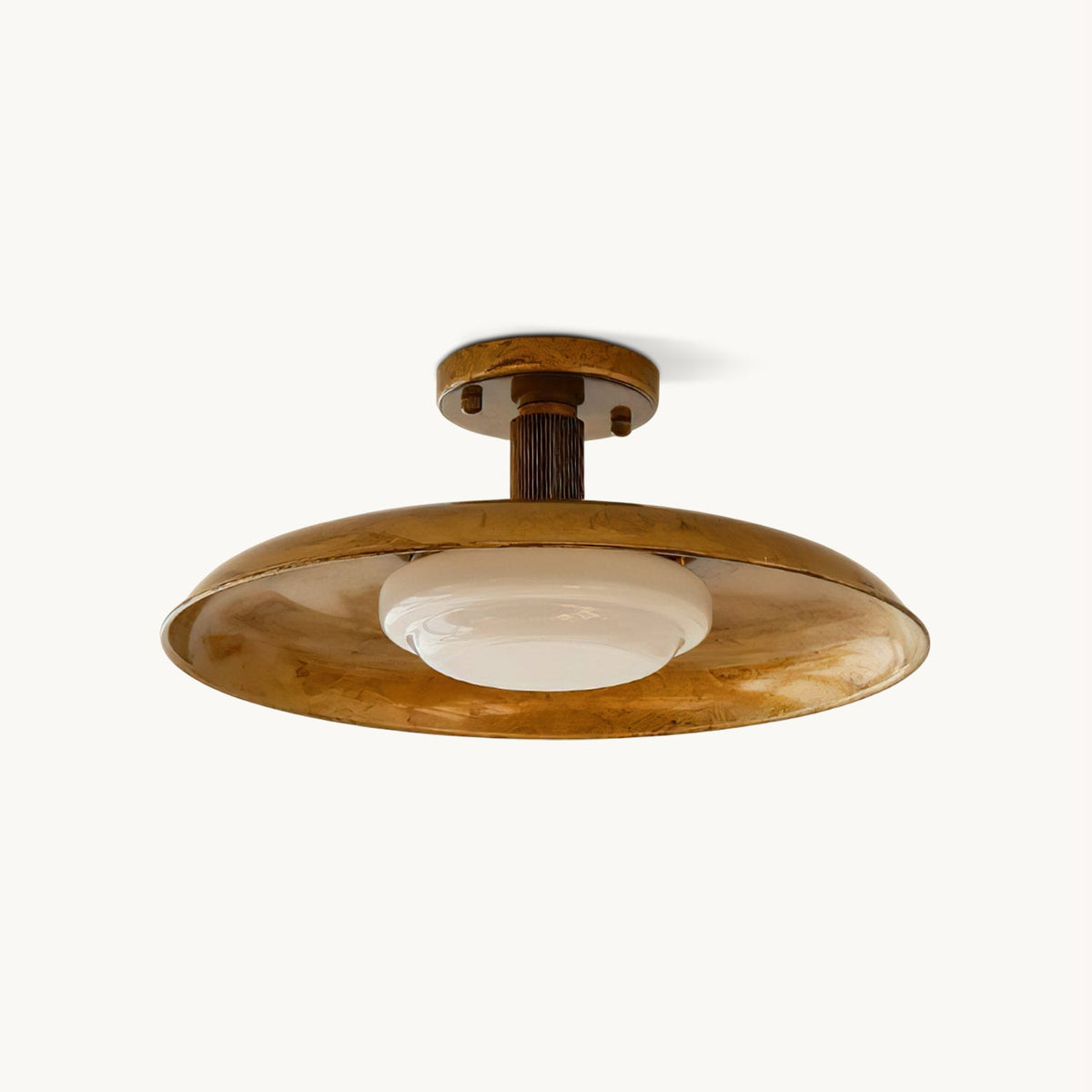 Gold Clérachic semi-flush ceiling light on a white backdrop, with a wide dish shade, a ribbed stem and a white glass diffuser.