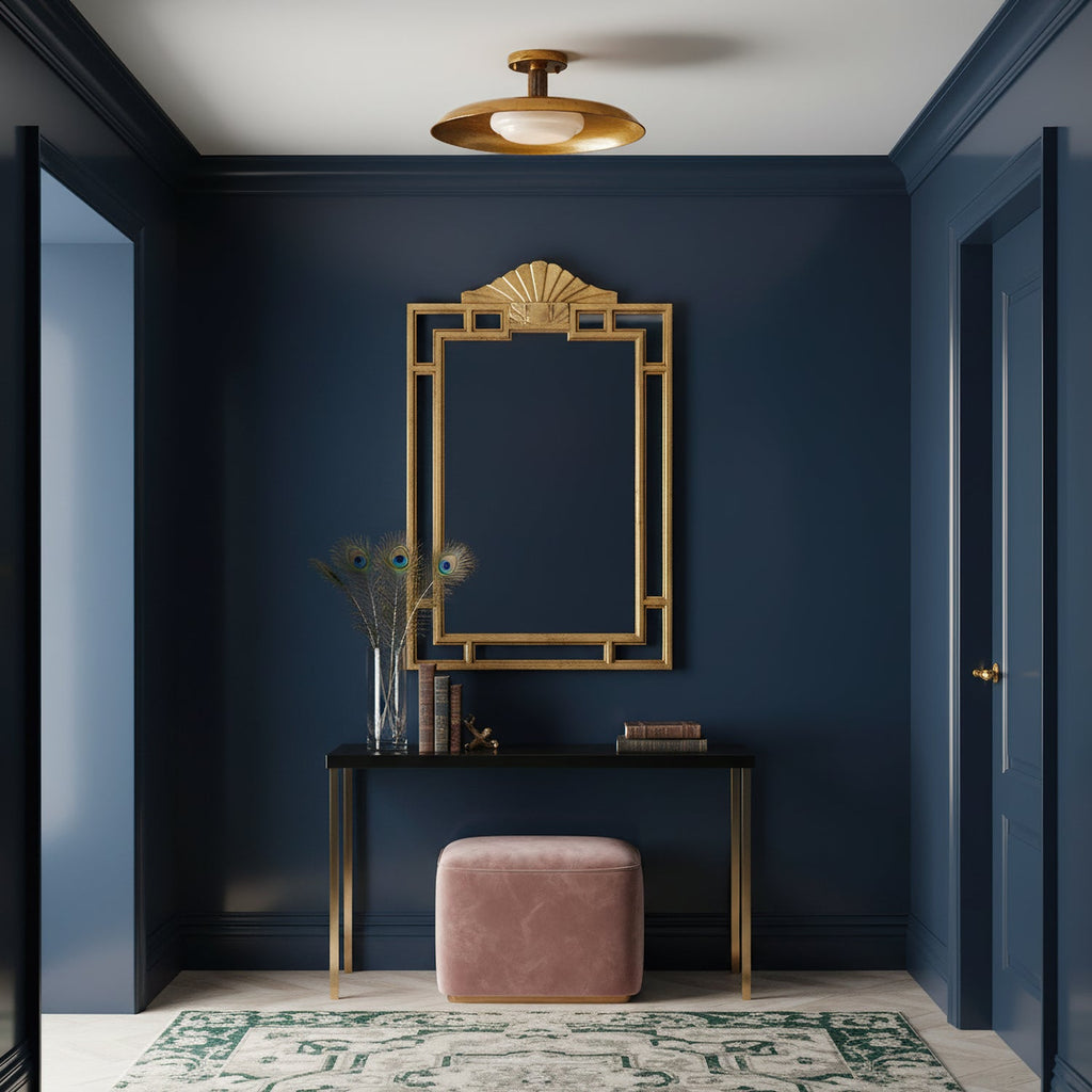 Clérachic gold ceiling light in a navy hallway, above a console with a gilt mirror and a pink pouffe.