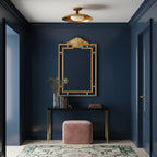 Clérachic gold ceiling light in a navy hallway, above a console with a gilt mirror and a pink pouffe.