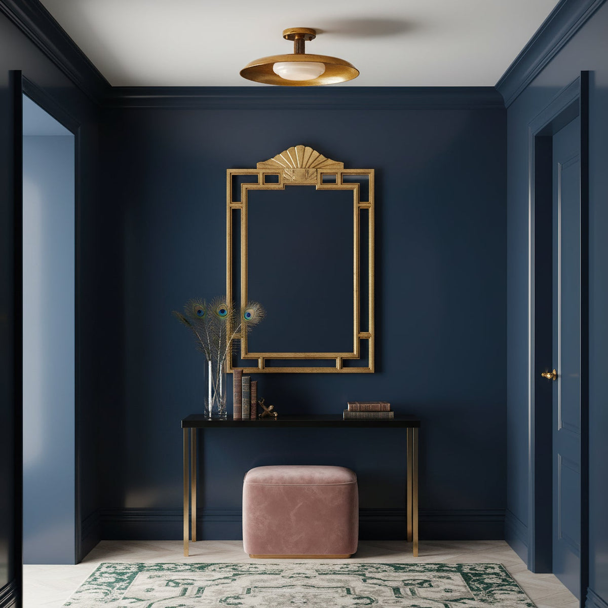 Clérachic gold ceiling light in a navy hallway, above a console with a gilt mirror and a pink pouffe.
