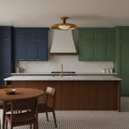 This Clérachic gold dish ceiling light hangs above a kitchen island, with navy and green cabinets and a white range hood.