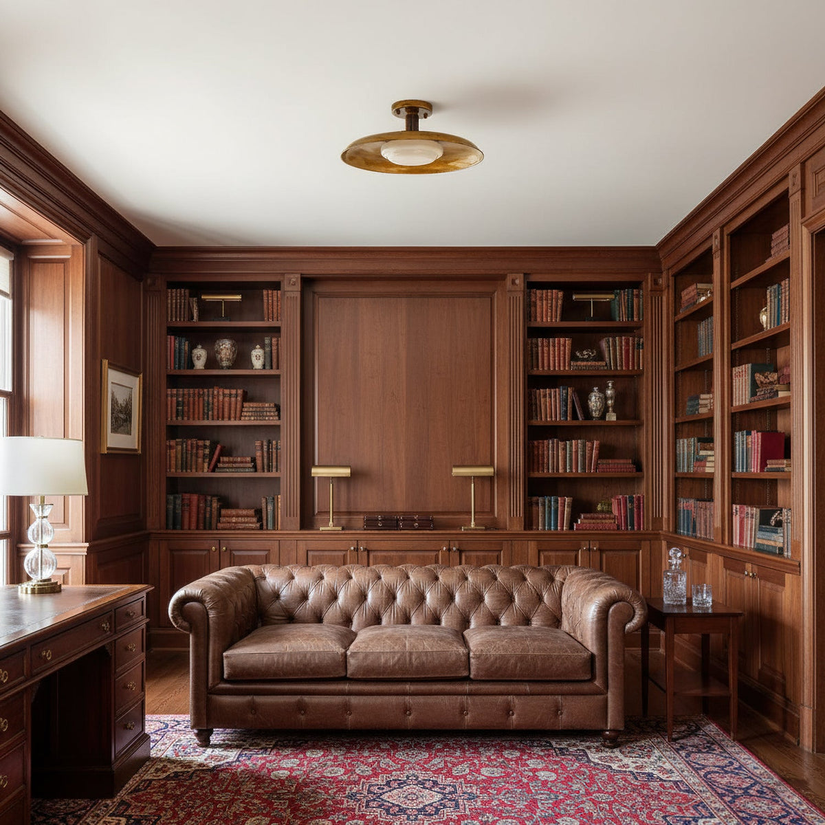 Clérachic gold dish ceiling light in a wood-panelled study with a tufted leather sofa and full bookshelves.