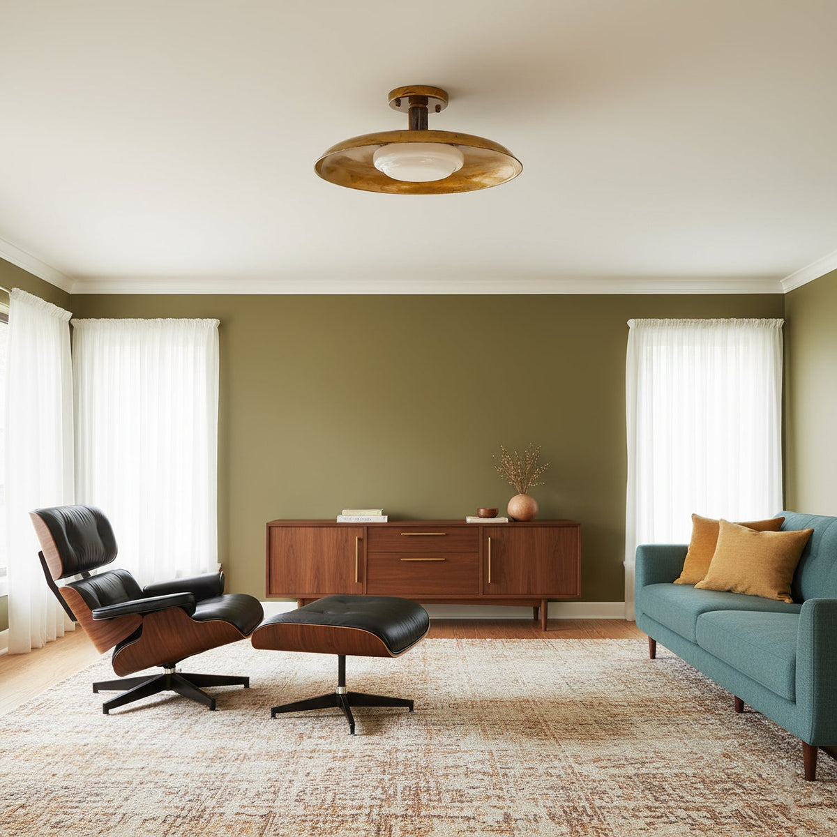 A Clérachic gold ceiling light in an olive-walled living room with a leather lounge chair and a teal sofa.