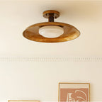 Side view of this Clérachic gold ceiling light, showing the shallow dish, the short stem and the white glass diffuser.