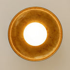 Looking straight up at this Clérachic ceiling light, with its lit round diffuser in the centre of a mottled gold dish.
