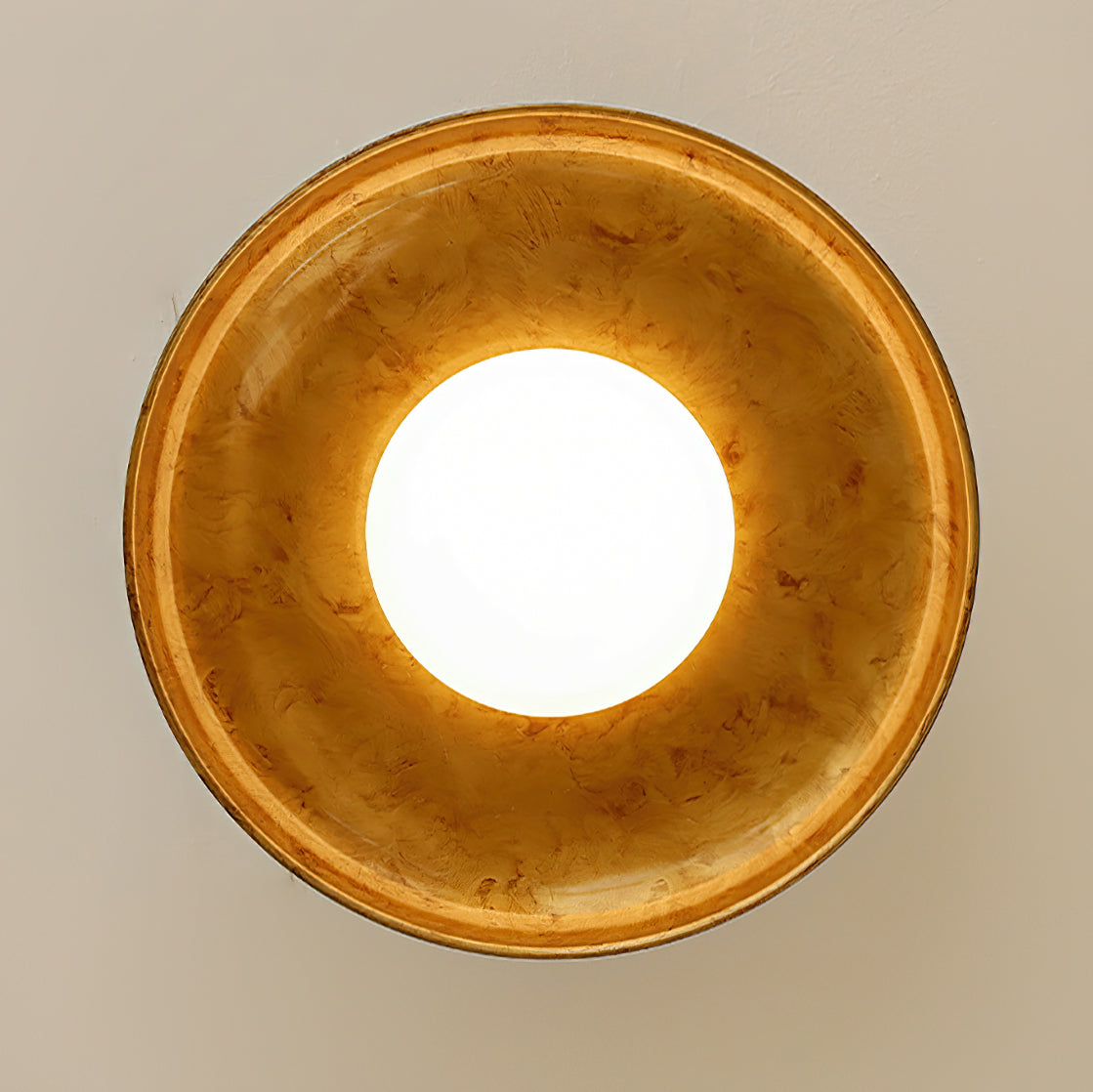 Looking straight up at this Clérachic ceiling light, with its lit round diffuser in the centre of a mottled gold dish.