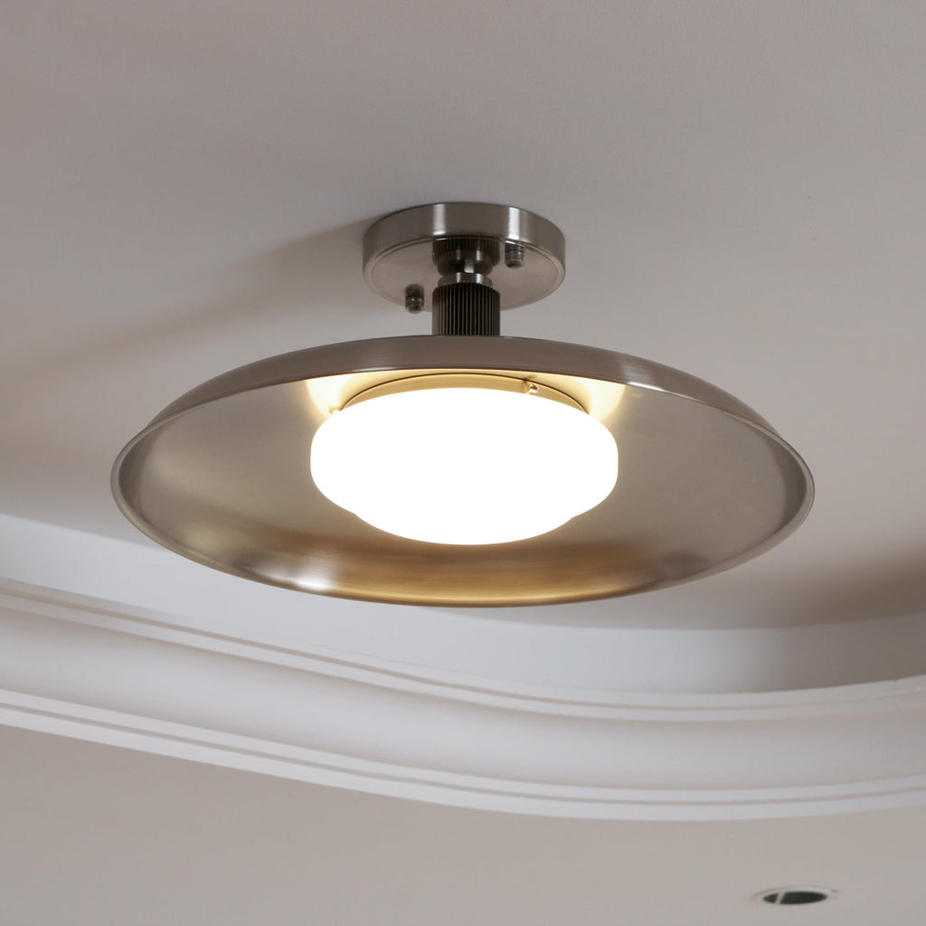 Close view from below of this Clérachic nickel ceiling light, with a lit white diffuser and a short nickel stem.