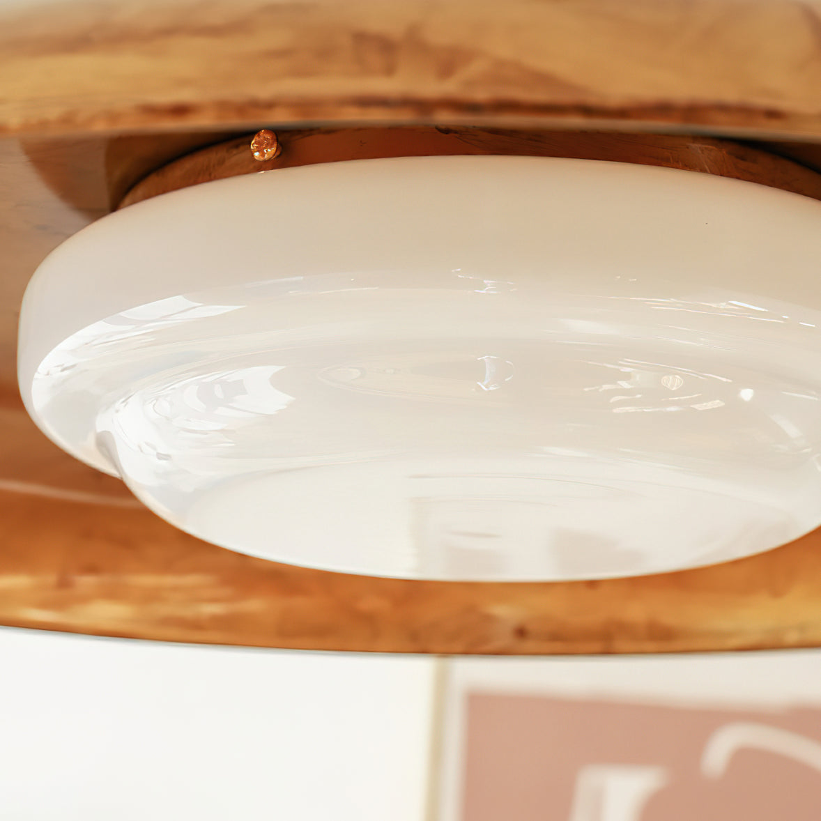 Close view of the opal white glass diffuser on this Clérachic ceiling light, with the gold dish behind it.