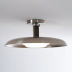 Wider view of this Clérachic nickel ceiling light, lit warm, with a ribbed dark stem and a broad shallow dish.