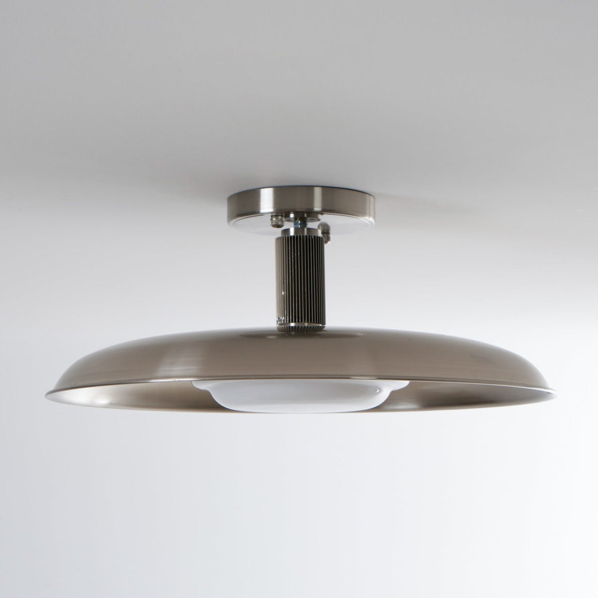Low view of this Clérachic nickel ceiling light, unlit, with a ribbed stem and the white diffuser tucked under the dish.