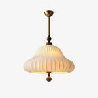 A Clérachic pendant on a plain light backdrop, with a brass canopy and rod, a walnut turned finial and a white pleated bell shade.