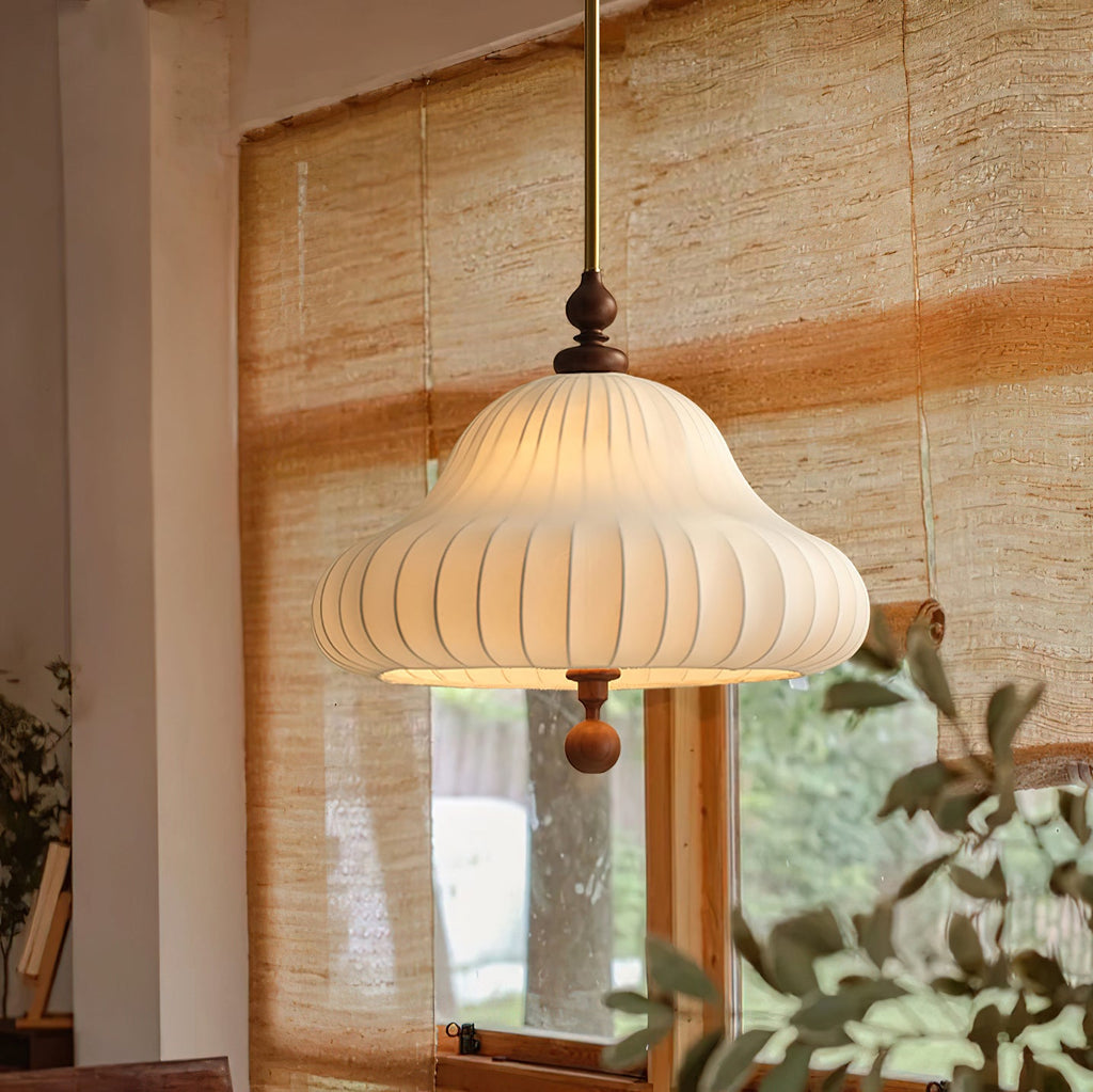 Hanging before a woven bamboo blind and a green leafy plant, this Clérachic pendant gives off a warm light through its white shade.