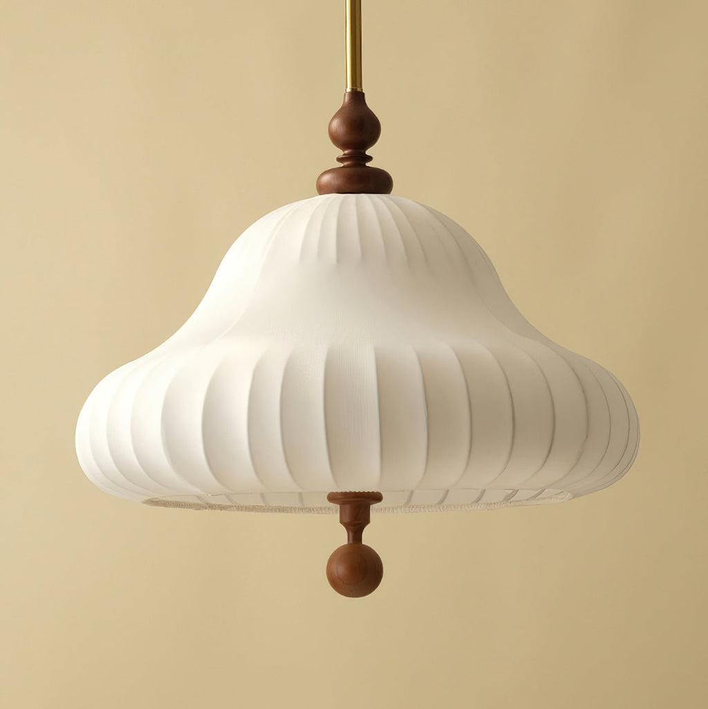 Close view from below of the ribbed white fabric shade, walnut neck and walnut ball drop on this Clérachic pendant, against a sand-coloured wall.