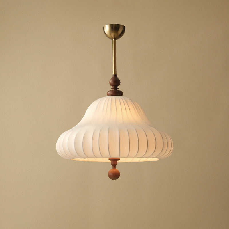 This Clérachic pendant on a warm beige backdrop shows its brass canopy, thin rod, walnut finial and softly glowing pleated shade.