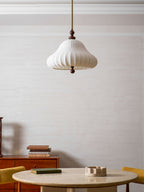 Low angle of this Clérachic pendant unlit above a round stone table, with the ribbed white shade and walnut ball drop clear.