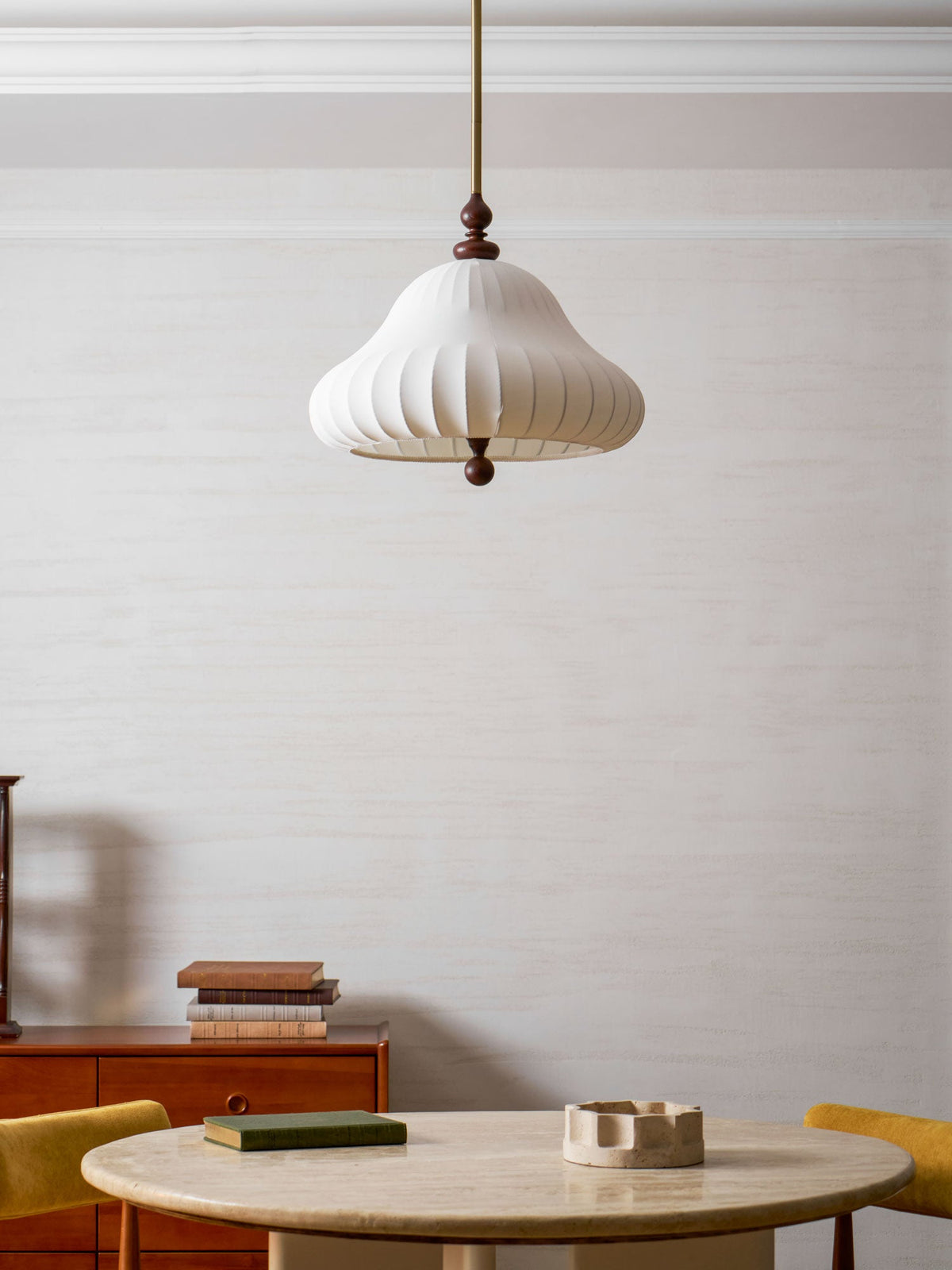 Low angle of this Clérachic pendant unlit above a round stone table, with the ribbed white shade and walnut ball drop clear.