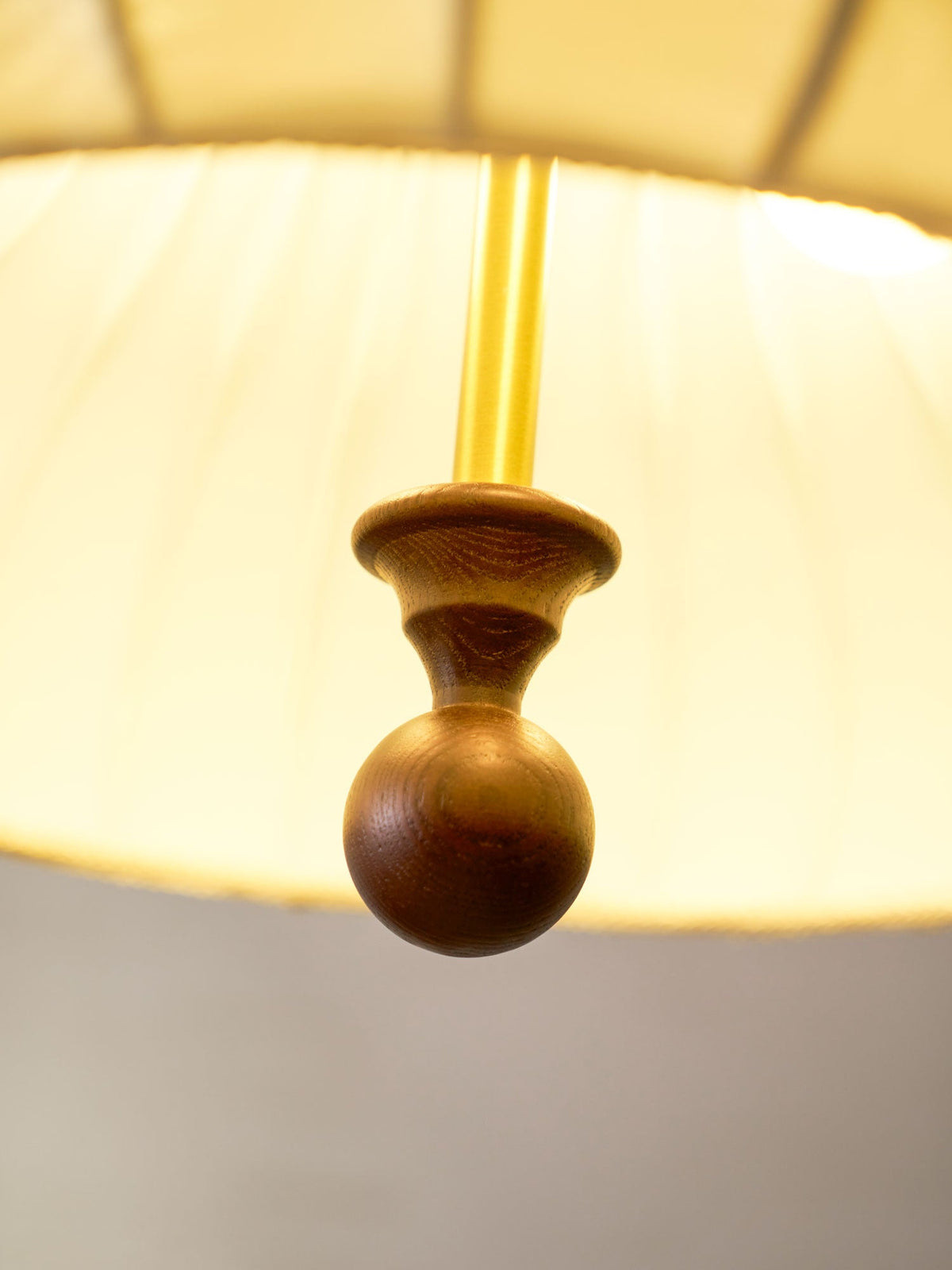 Looking up inside the glowing white shade of this Clérachic pendant, the brass rod ends in a turned walnut ball.