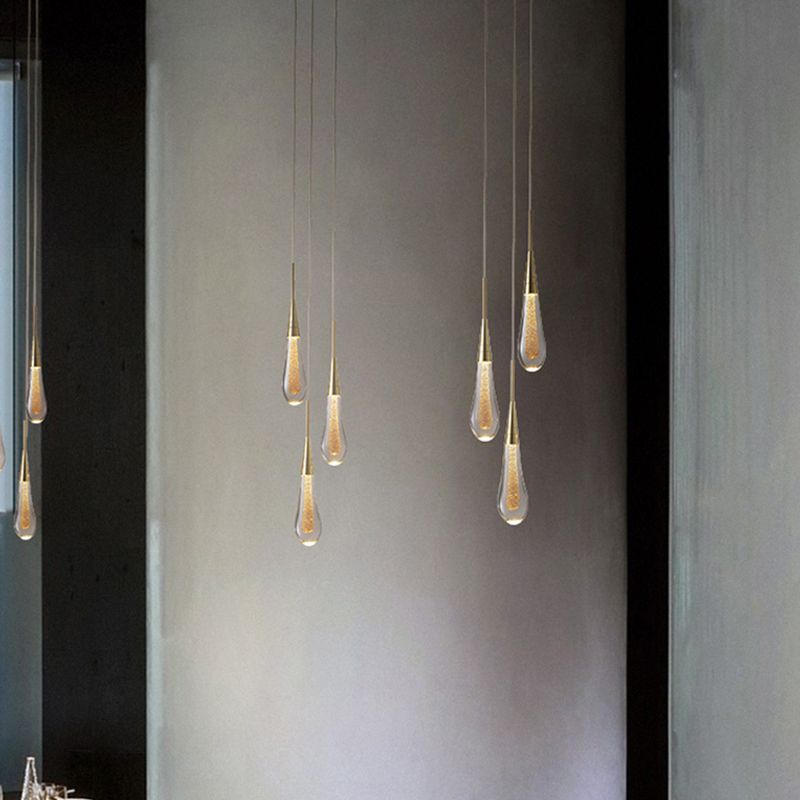 Clérachic Gold-Flecked Glass Teardrop Pendant Lights grouped at staggered heights down a tall concrete stairwell wall, lit.