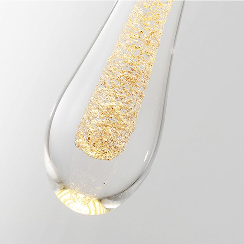 Macro of a Clérachic teardrop pendant drop, coarse gold flakes suspended in a column inside the clear glass.