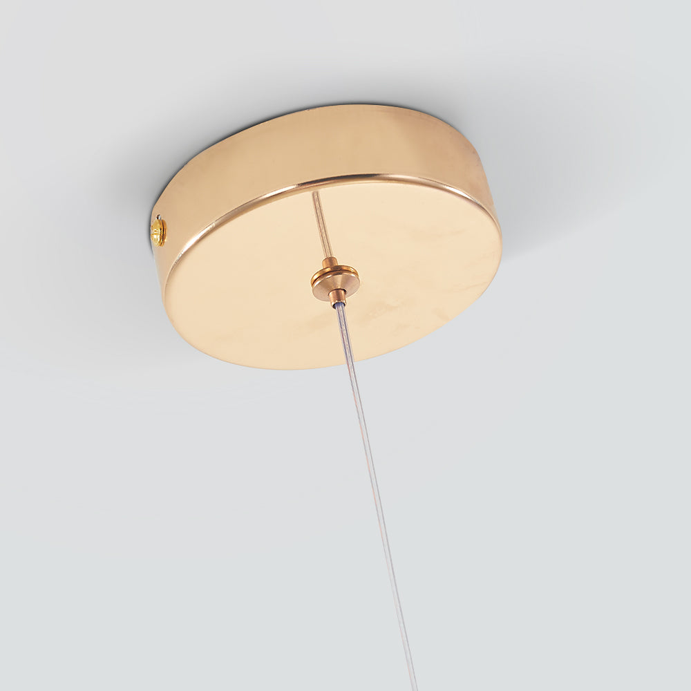 Close view of the round polished gold ceiling canopy on the Clérachic gold-flecked teardrop pendant, clear cable dropping away.