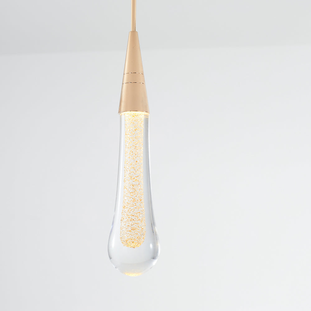 A lit Clérachic Gold-Flecked Glass Teardrop Pendant Light, its gold-flake core glowing amber and the rounded tip catching light.