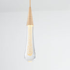 A lit Clérachic Gold-Flecked Glass Teardrop Pendant Light, its gold-flake core glowing amber and the rounded tip catching light.