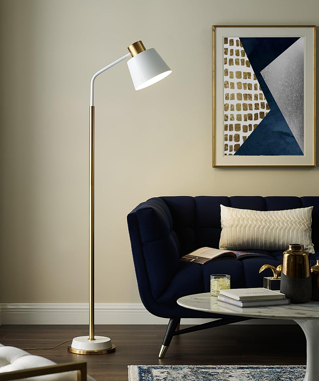 A Clérachic floor lamp with a white shade leans over a navy velvet sofa, beneath a blue and gold abstract print.