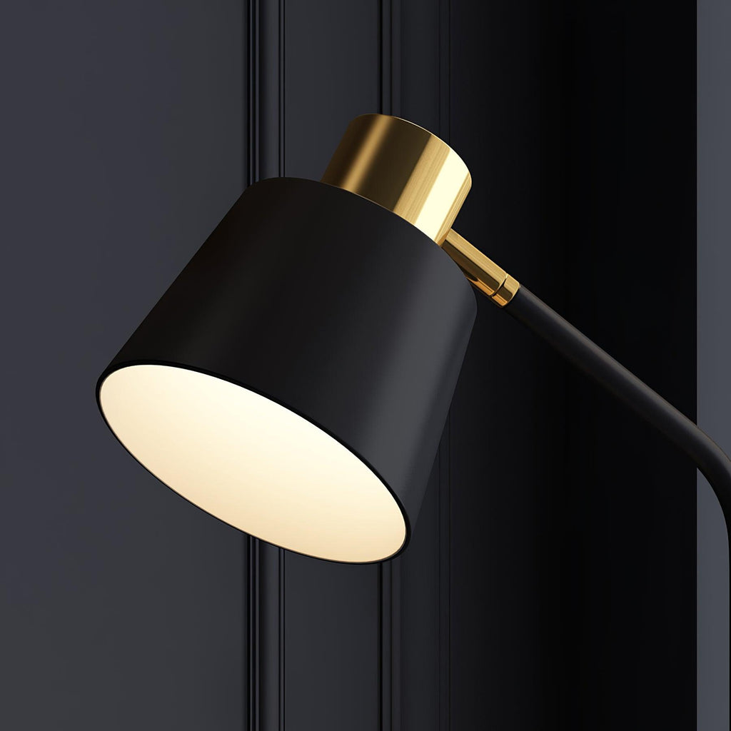 Close view of the black conical shade and brushed gold cap on this Clérachic floor lamp, against a dark panelled wall.