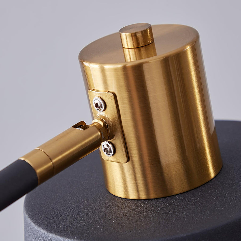 Close view of the brushed gold shade cap, screw plate and joint that let this Clérachic floor lamp's shade swivel.