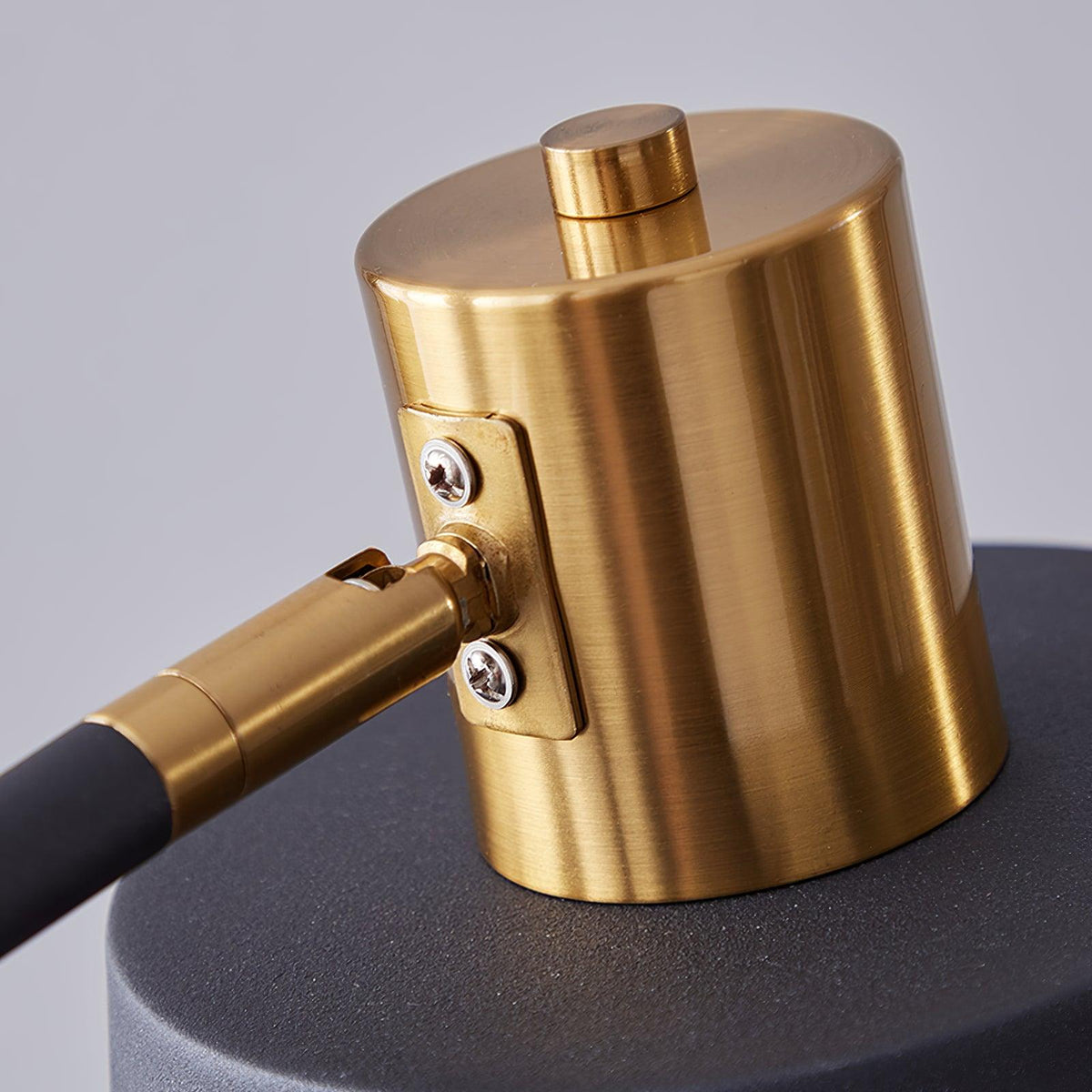 Close view of the brushed gold shade cap, screw plate and joint that let this Clérachic floor lamp's shade swivel.
