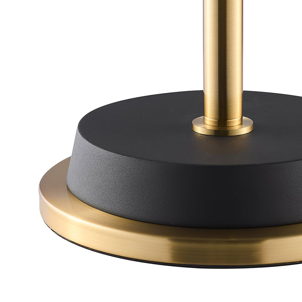 Close view of the black base with a gold rim and the gold stem rising from it on this Clérachic floor lamp.
