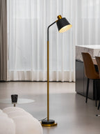 Full-length Clérachic floor lamp in black and gold, lit beside sheer curtains, brown dining chairs and a marble counter.