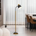 Clérachic floor lamp with a black shade glowing beside a dining area, with leather chairs and a boucle seat in view.