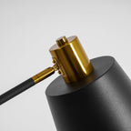 Close view of the textured black shade and gold cap on this Clérachic floor lamp, on a light grey backdrop.