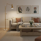 Gold pole and cone shade of this Clérachic floor lamp beside a beige sofa and pale coffee table, with three framed prints above.