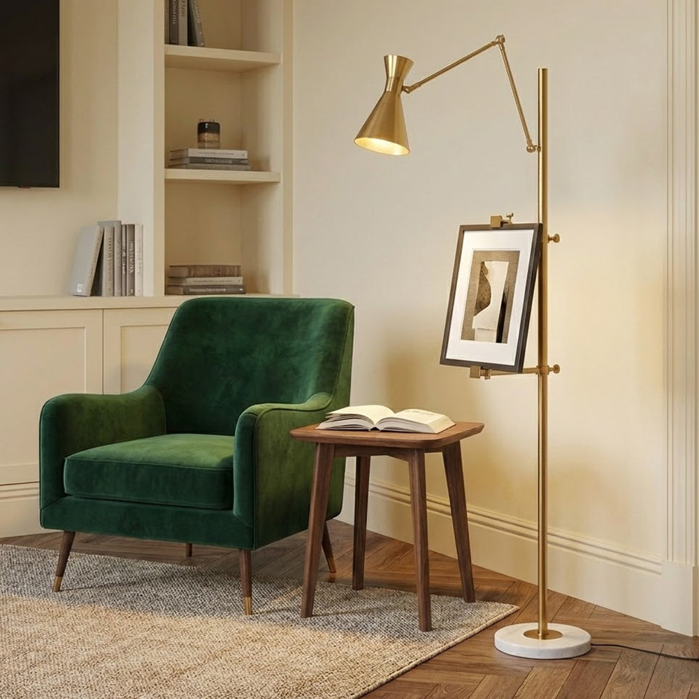 Gold Clérachic floor lamp with a small framed picture clipped to its pole, beside a green velvet armchair and a walnut side table.