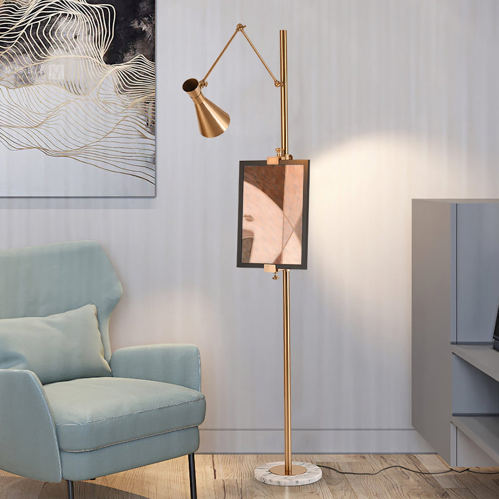 Gold Clérachic floor lamp with a framed copper-toned print on its pole, beside a pale blue armchair and a marble base.