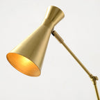 Close view of the gold cone shade and arm joint of this Clérachic floor lamp, with a warm brass interior to the shade.